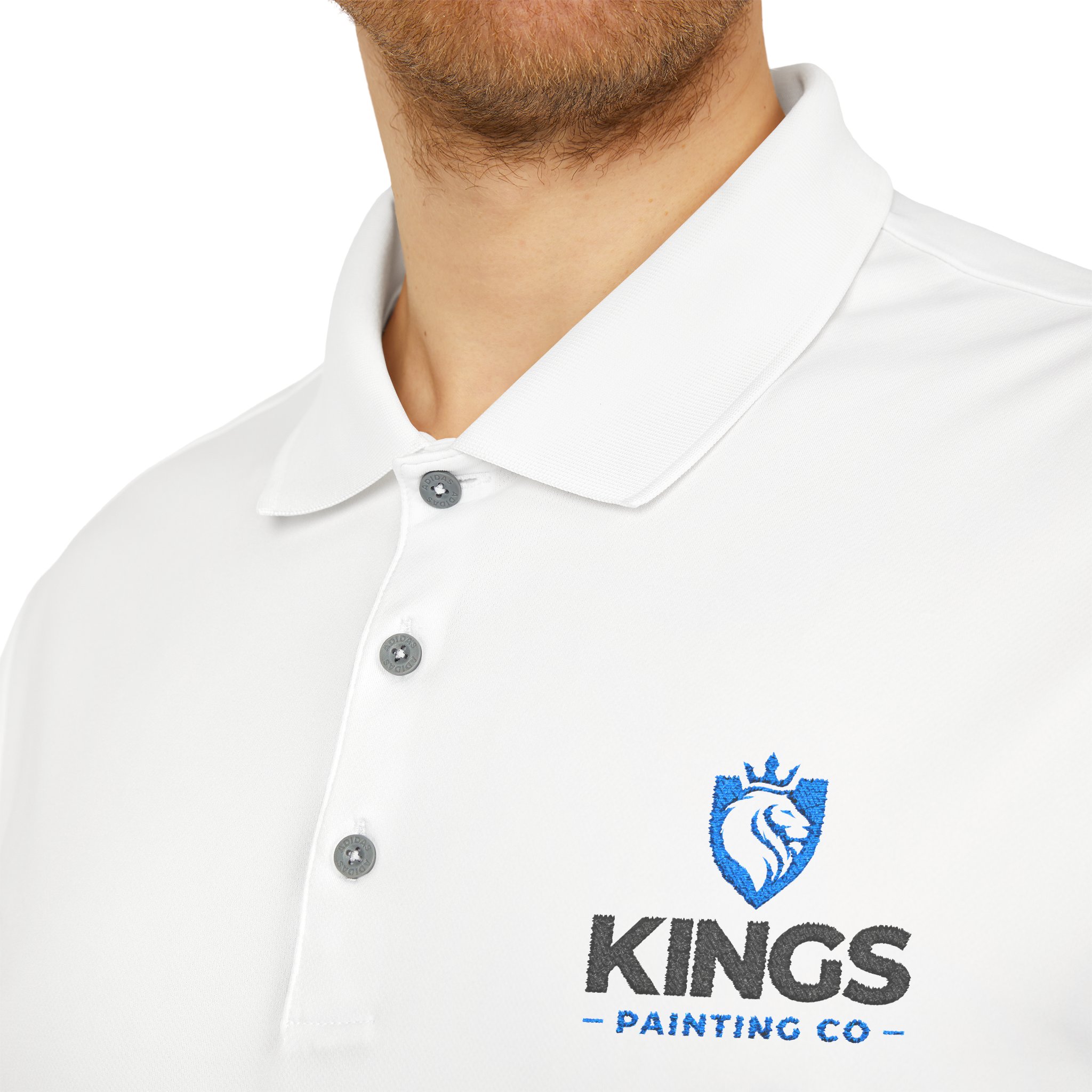 Close-up of a person wearing the Kings Painting Co. Performance Polo by Under Armour®, featuring "KINGS PAINTING CO" and a blue lion logo embroidered on the left chest. The person's face is partially out of frame.